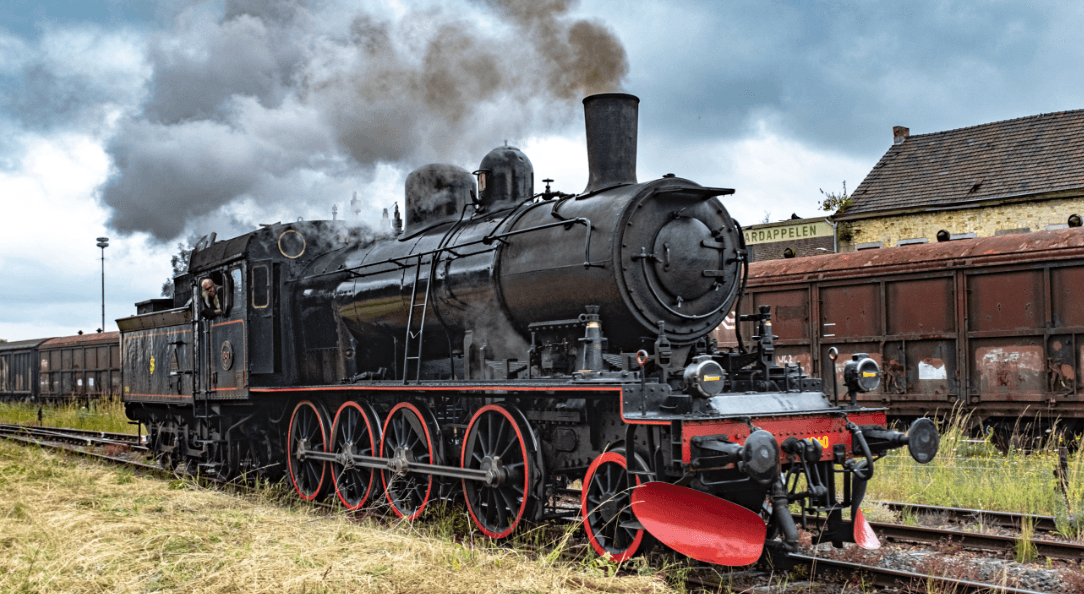 A black steam locomotive with red wheels on a railway track